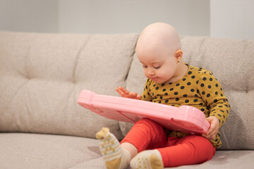 Baby girl with cancer and hair loss due to chemotherapy playing with a piano