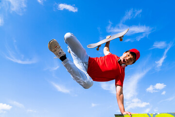 young man posing happy with skateboard in hand background blue and cloudy. youth sports and...