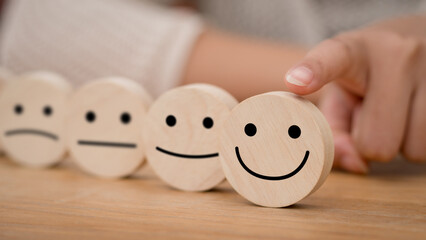 Hand of a businessman chooses a smile face on wood block circle. customer services best excellent...