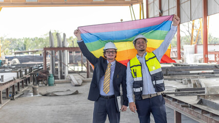 Two engineers with safety hat hold a flag to express their support to LGBT right in a construction...