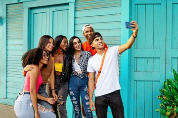 Big group of cheerful young friends taking selfie portrait. Happy people looking at the camera smiling. Concept of community, youth lifestyle and friendship.
