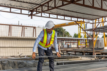 A black male constructer or worker is preparing steel bars to make concrete floor foundation in a factory