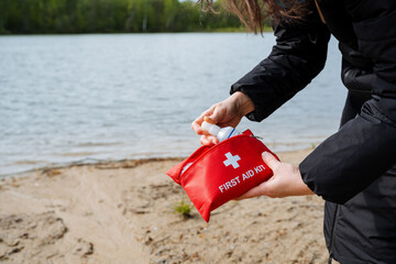 Woman with first aid kit near lake, ready for fun recreation on beach