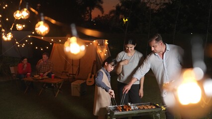 Family celebrate holiday in garden. Father, mother and child grill food for member. Outdoor camping...