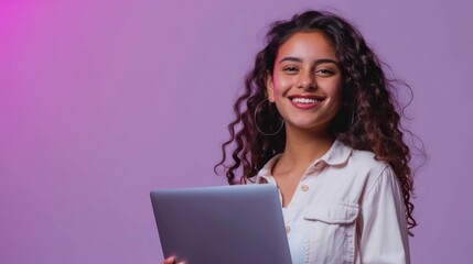A smiling young Hispanic woman, self-employed and confident, standing in a studio with a laptop in hand against a vibrant violet background. 
