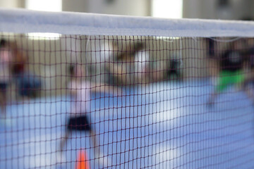 A badminton net is seen with a kid playing in the background