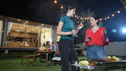 Family gather celebrate holiday. Focus Mother and grandmother drink wine and grill food for family...