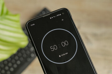A phone with a black and white 50-minute timer to study with the pomodoro method on a blurry...