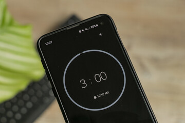 A phone with a black and white 3-minute timer to study with the pomodoro method on a blurry...