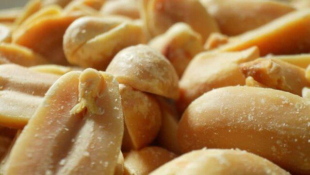 Behold the close-up spectacle of roasted peanuts, gleaming with a golden-brown sheen. Split in halves, they disclose their velvety essence, adorned with glistening salt crystals, tempting the senses.
