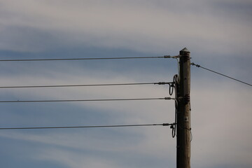 A tall wooden pole with three wires hanging from it