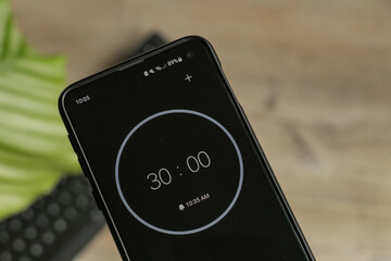 A phone with a black and white 30-minute timer to study with the pomodoro method on a blurry...