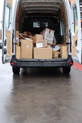 A white van is filled with boxes and is parked on a wet street