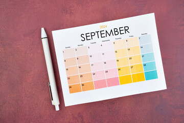 September 2024 calendar page and pen on red retro background.