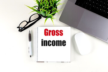 GROSS INCOME text on notebook with laptop, mouse and pen