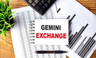 GEMINI EXCHANGE text on notebook on chart with calculator and pen