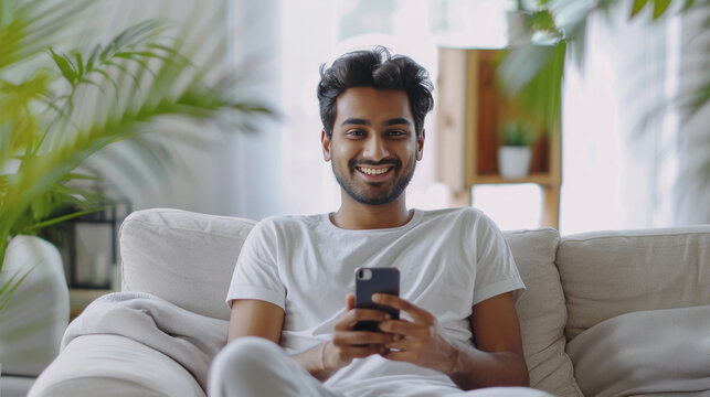 young indian man holding smartphone at home - Powered by Adobe