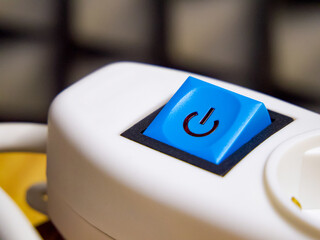 Close-up of a blue button, icon, on white equipment, indicating operation and control.