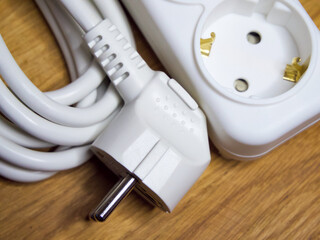 A white power plug and coiled cable on a wooden surface, indicating electrical connectivity.