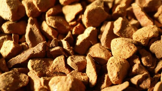 Freeze-dried coffee granules, bathed in warm light, flaunt their rugged, golden-brown contours. Each piece whispers tales of aroma and flavor in its irregular, coarse texture.
