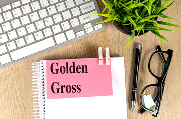 GOLDEN GROSS text pink sticky on notebook with keyboard, pen and glasses