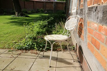 Stillleben als Symbol für Ruhe / Auszeit / Ruhestand - Einsamer alter Stuhl steht verlassen auf Terrasse von bäuerlichem Haus/ Fachwerkhaus