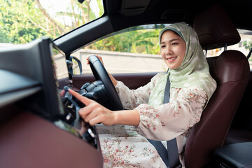 Asian muslim islamic woman smiling happily driving in a car traveling using automobile for...