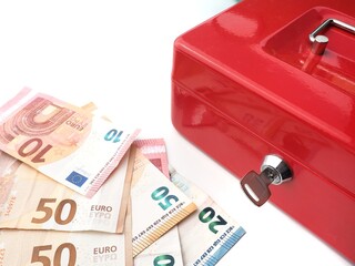 Close-up of a red money box with a key and euro banknotes on a white background, symbolizing savings and financial security