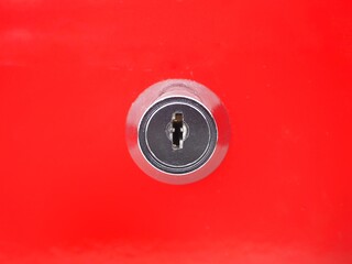 Isolated round keyhole on a red metal background, without a key. Security, safety, and mystery concepts