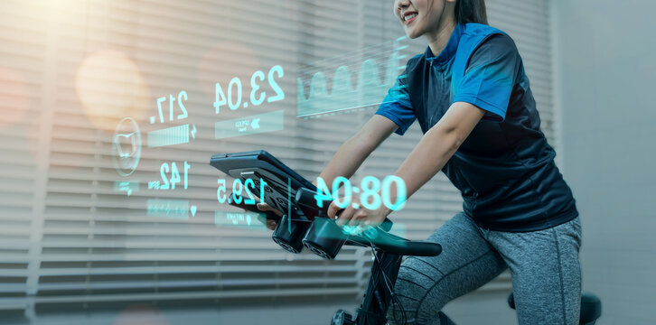 Cycling at home using a stationary exercise bike, with tracking heart rate for a healthy lifestyle graphical ui display technology, workout daily leisure routine, racing sport activity training.
