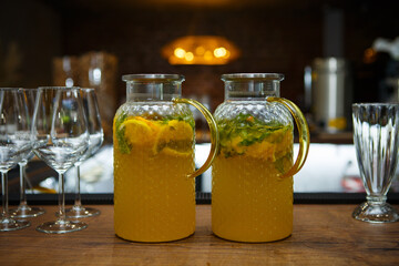 Two carafes of  orange squash with orange slices and mint