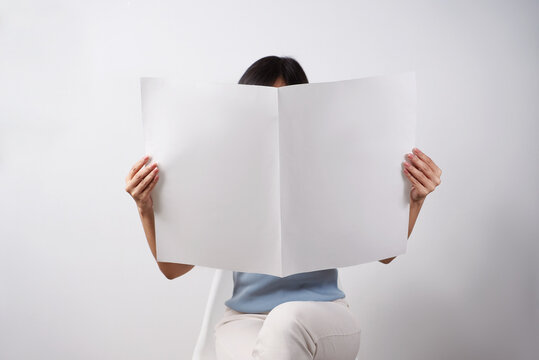 Woman reading mockup of blank newspapers to add your own news isolated on white background.