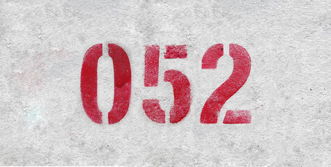 Red Number 052 on the white wall. Spray paint.