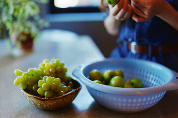 Woman holding a bowl of fresh green grapes surrounded by additional bowls of ripe green grapes