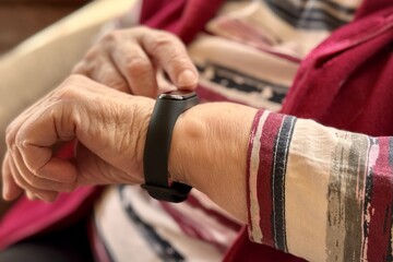 The black smart band with display touchpad and heart rate monitor. The old woman sitting in...
