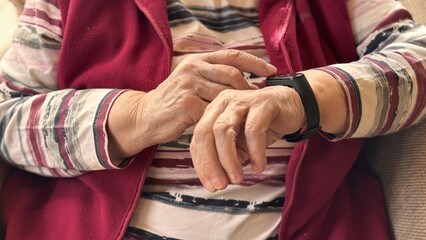 The black smart band with display touchpad and heart rate monitor. The old woman sitting in...