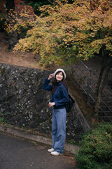 Asian woman in Japan's fall beauty, a cheerful holiday portrait in Kyoto. Vibrant foliage, friends, and smiles by the lake create a joyful and scenic atmosphere.