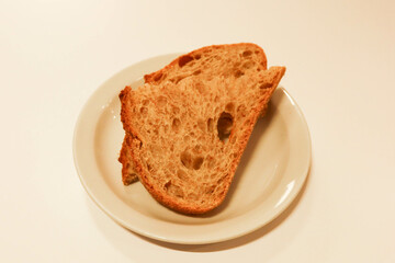 a half slice of brown sour dough bread on a white plate isolated in a white table background