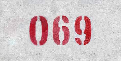 Red Number 069 on the white wall. Spray paint.