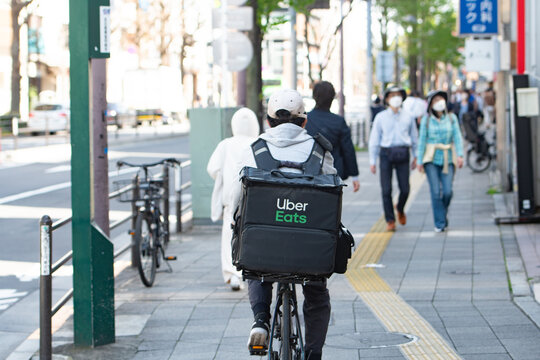 Tokyo, Japan - Aprili 7, 2024 : Uber Eats rider cycling in the street ,delivery service at Tokyo, Japan.