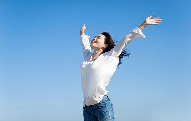 Woman with outstretched arms enjoying the wind and breathing fresh air. She is looking fresh, happy and energetic