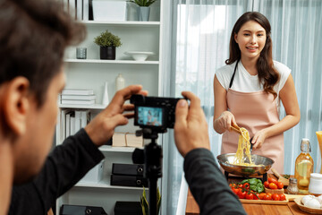 Cameraman recording to woman in chef influencer host cooking spaghetti with meat topped tomato...