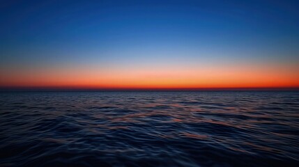  A breathtaking image of the sun setting over a tranquil sea, casting a palette of warm colors that blend seamlessly from deep orange to soft pink across the horizon.