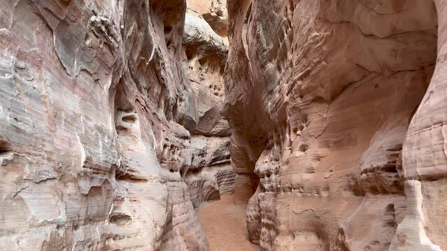 Personal perspective or hiker point of view walking through the beautiful, pink and narrow rock walls of Kaolin Slot Canyon in slow motion - Valley of Fire State Park, Nevada, USA