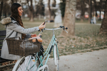 A professional woman enjoys a leisurely bike ride in the park and stops to use her smart phone.