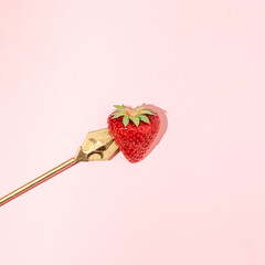 Heart shaped strawberry stubbed with golden arrow, minimal love concept