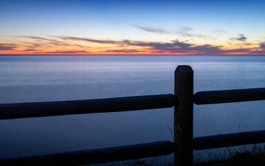 Fence in front of water at sunset