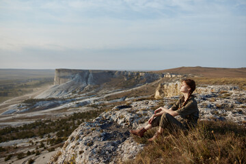 Woman contemplating majestic landscape of valley and mountains on cliff edge travel adventure...