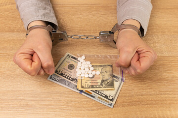 Woman in handcuffs with medicine and dollars. The concept of drug addiction. Drug crime.