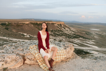 Woman sitting on rock with mountain view, travel and adventure concept